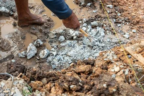 Construction work in progress worker digging in muddy ground at a building si Stockfoto's