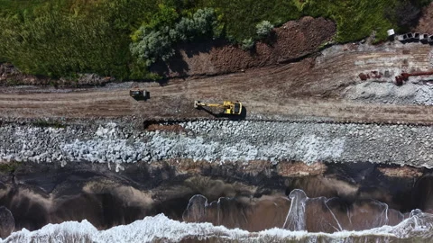 Construction work on a riverbank with heavy machines moving earth and rocks in a Stock Footage 339486782