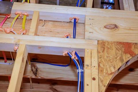 Construction work showing electrical, plumbing installations in wooden beams at Stock Photos