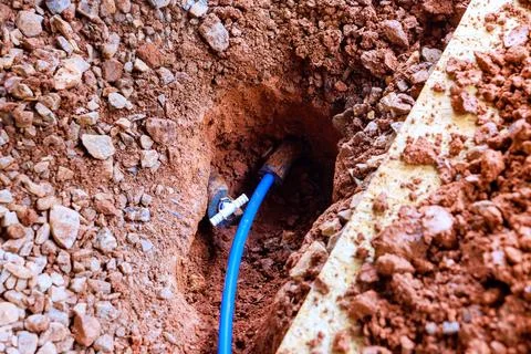 Construction work shows blue pipe placed in hole surrounded by soil rocks Fotos Stock