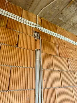 Construction work shows electrical wiring on brick wall at building site du.. Stock Photos