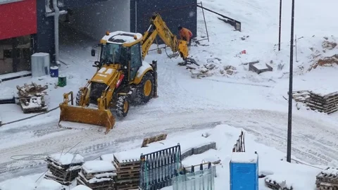 Construction work in snowy conditions at a site in the early morning hours with Stock Footage 330987619