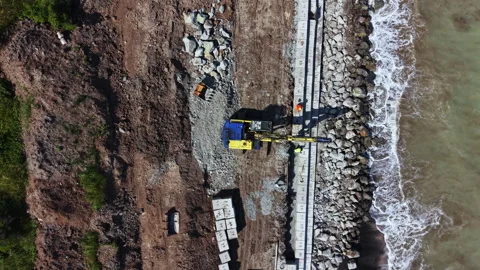 Construction work takes place along the shoreline as workers build a coastal Video stock 337913453