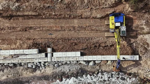Construction work takes place on a beach as workers lay down concrete blocks Stock Footage 335421248