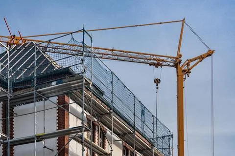 Construction work takes place on a building using a crane Stock Photos