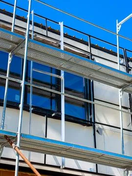 Construction work takes place on a building as workers use scaffolding to a.. Stock Photos