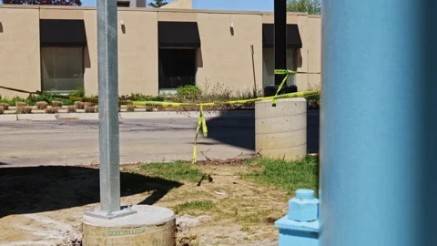 Construction work takes place near a building with safety tape blocking access Stock Footage 334156735