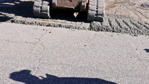 Construction work takes place on road as tractor machine spreads fresh concrete Stock Footage 338117511