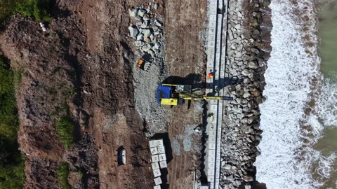 Construction work takes place on the shoreline with heavy machinery near a body Stock Footage 337903986