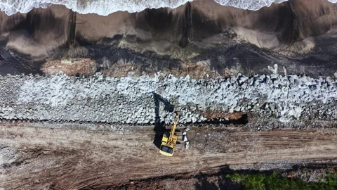 Construction work is taking place on a beach where rocks are being placed along Stock Footage 337947747