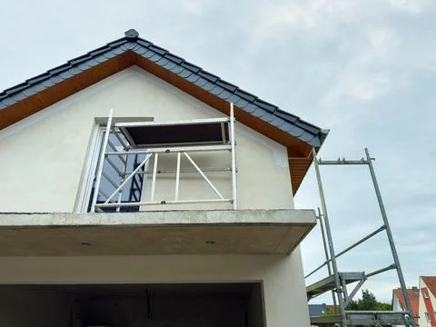 Construction work is taking place on a house, with scaffolding set up and a p 写真素材