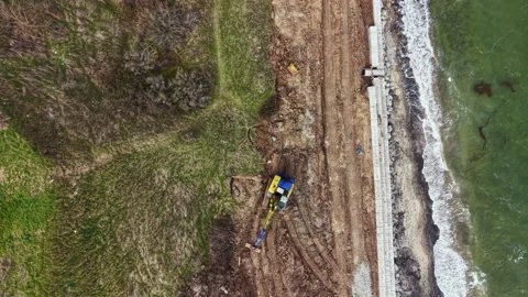 Construction work is taking place near the shoreline on a cloudy day with heavy Stock Footage 336541205