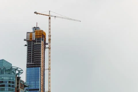 Construction work is taking place on a tall building in a city skyline duri.. Photos