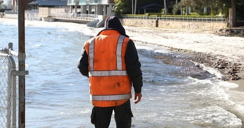 Construction worked looks down into dirty water with rubbish Stock Footage 91471302