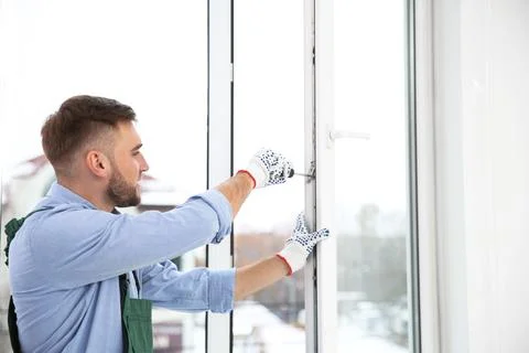 Construction worker adjusting installed window with screwdriver indoors Stock Photos