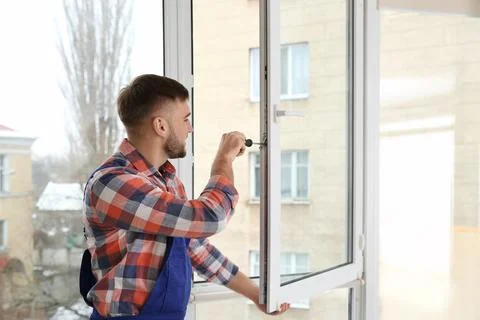 Construction worker adjusting installed window with screwdriver indoors 스톡 사진