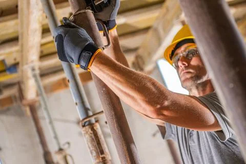 Construction Worker Adjusting Support Beam in a Building Under Renovation Fotos de archivo