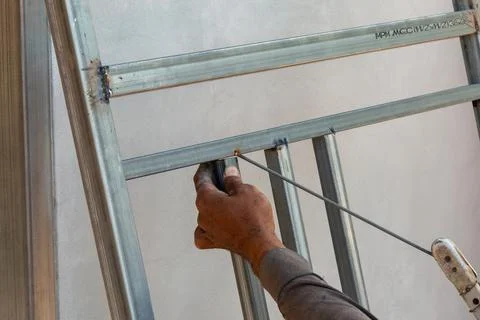 Construction worker adjusts metal frame structure in workshop industrial se.. Stock Photos