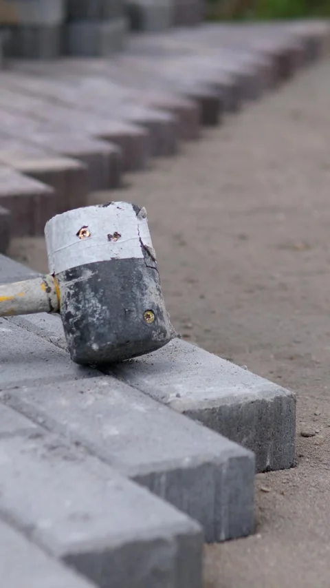Construction worker aligning gray paving stones along outdoor curb line with Stock Footage 347919193