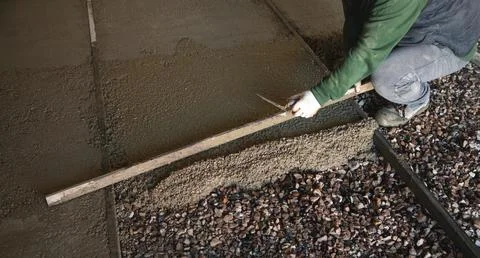Construction worker aligns concrete screed floor. Stock Photos