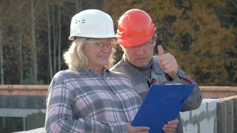 Construction worker and architect reviewing plans on building site Stock Footage 316886823
