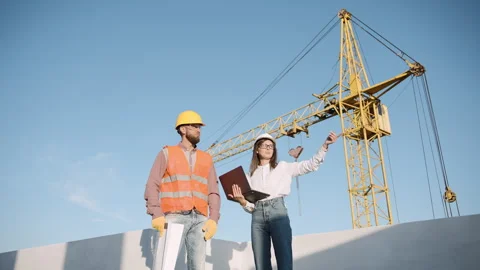 Construction worker and engineer collaborating on site with laptop and plans Stock-Footage 295957959