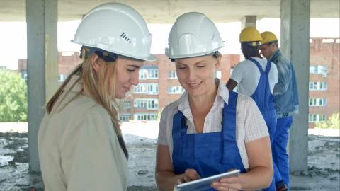 Construction worker and engineer working on building site, using digital tablet Stock Photos