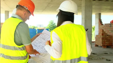 Construction worker and female engineer look at blueprint Stock Footage 317611892