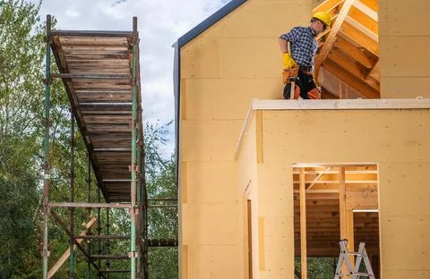 Construction Worker and the Newly Built Small Wooden Residential House 스톡 사진