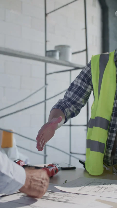 Construction Worker and Site Manager Shaking Hands over Floor Plans Stock Footage 332249761