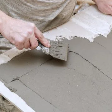 A construction worker applies cement to ceramic tile with a spatula Stock-Fotos