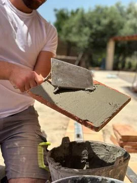A construction worker applies mortar to a tile using a trowel . Foto stock