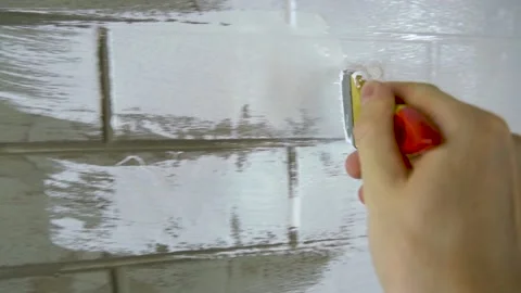 A construction worker applies paint to a brick wall. Stock Footage 141762612
