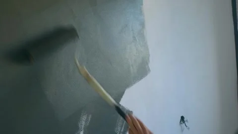 Construction worker applies paint to wall with roller Stock Footage 280302135