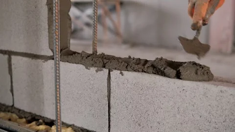 Construction worker apply cement between bricks to build a wall in a building Video stock 292619239