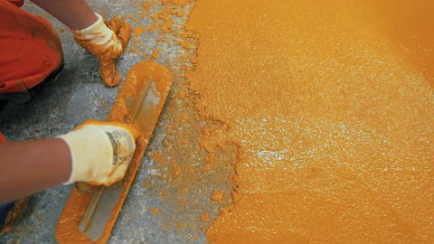 A construction worker apply epoxy resin in an industrial hall Stock Footage