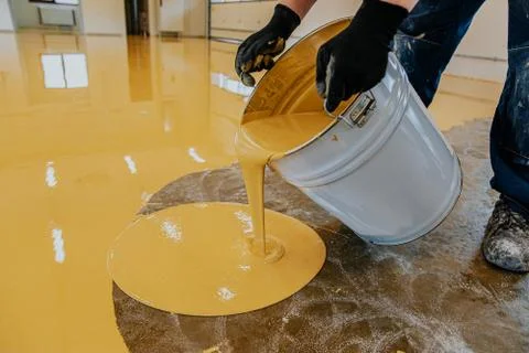 A construction worker apply epoxy resin in an industrial hall Stock Photos