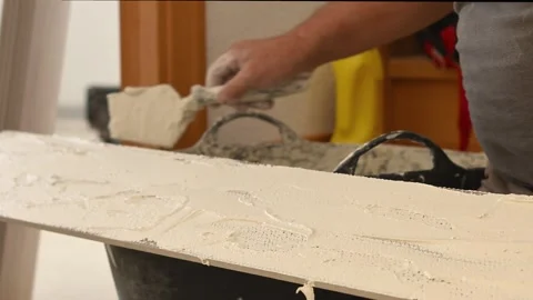 Construction worker applying adhesive to a ceramic tile Stock Footage 346448761