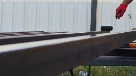 Construction worker applying black paint on metal beams, protecting steel Vidéo 315357663