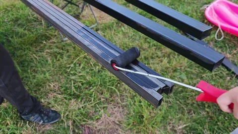 Construction worker applying black protective coating on metal bars, painting Vidéo 315359377