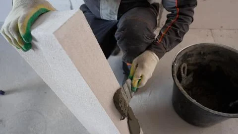 Construction worker applying cement on aerated concrete brick Stock Photos