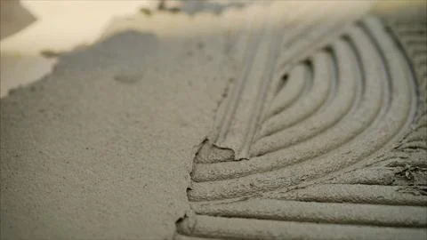 Construction worker applying cement glue mixture on wall with notched trowel Stock Photos
