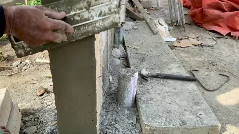Construction worker applying cement plaster to a concrete pillar Видео 334533355