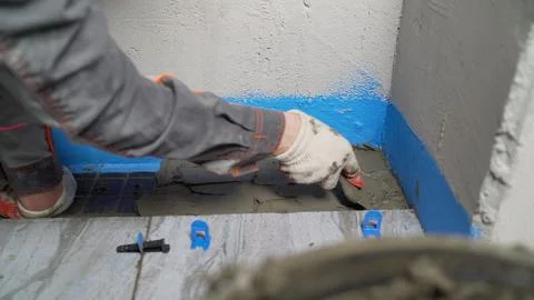 Construction worker applying cement on tiles with trowel Stock Photos