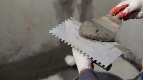 Construction worker applying cement on trowel with spatula Stock Photos