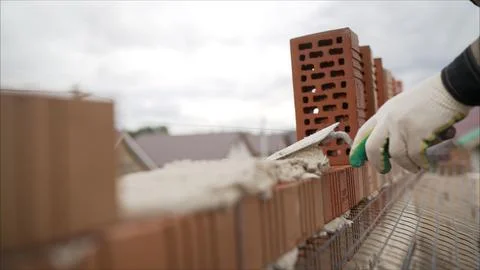 Construction worker applying cement with trowel on brick wall Stock Photos