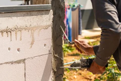 Construction worker applying cement wall outdoor site industry work daytime.. Foto stock