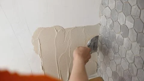 Construction worker applying grout on gray tiles Stock Photos