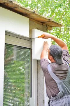 Construction worker applying insulation over exterior wall of house Foto stock