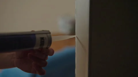 Construction worker applying liquid nails adhesive to door frame during home Stock Footage 307143629